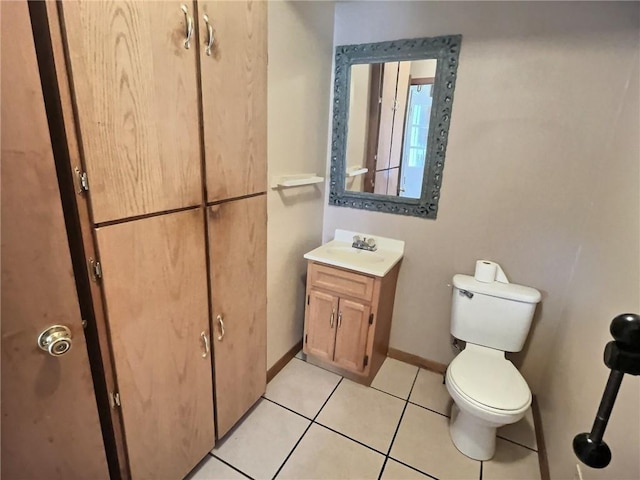 half bath with toilet, tile patterned floors, baseboards, and vanity