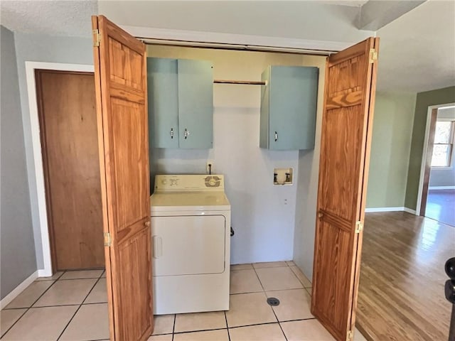 washroom featuring washer / clothes dryer, cabinet space, baseboards, and light tile patterned floors