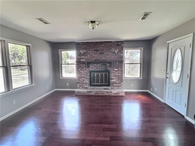 unfurnished living room with a fireplace, visible vents, and a wealth of natural light