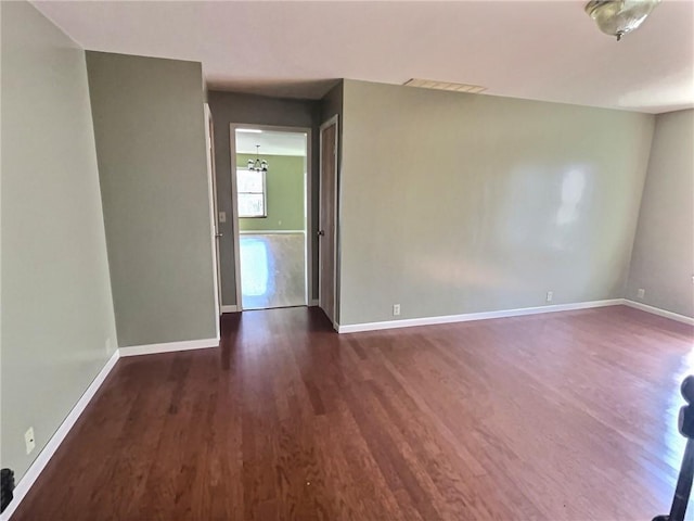 unfurnished room featuring visible vents, baseboards, and dark wood-type flooring