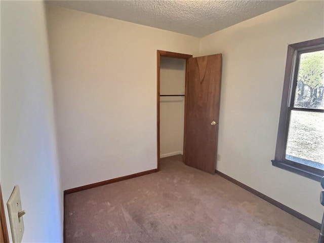 unfurnished bedroom featuring a textured ceiling, a closet, carpet flooring, and baseboards