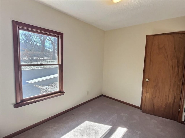 carpeted empty room featuring baseboards