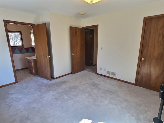 unfurnished bedroom with baseboards, visible vents, and light colored carpet