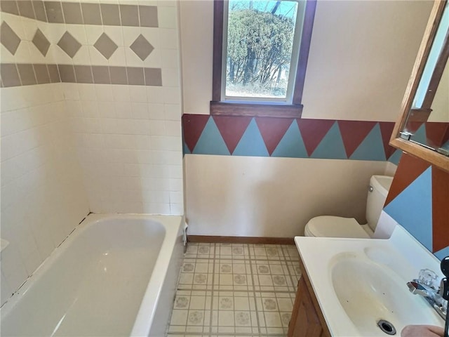 full bath featuring toilet, vanity, baseboards, a tub, and wallpapered walls