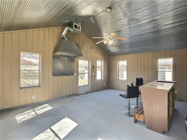 interior space featuring vaulted ceiling, concrete floors, visible vents, and wooden walls