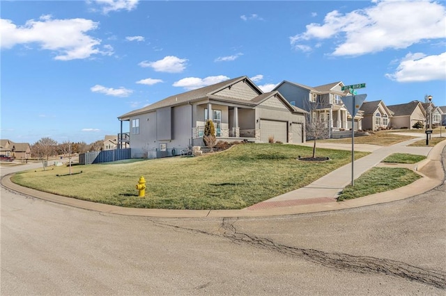 view of front of house featuring an attached garage, fence, driveway, a residential view, and a front lawn