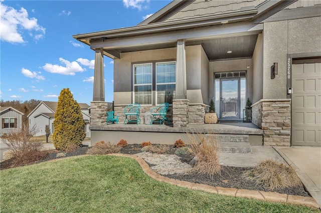 view of exterior entry with stone siding, covered porch, an attached garage, and stucco siding