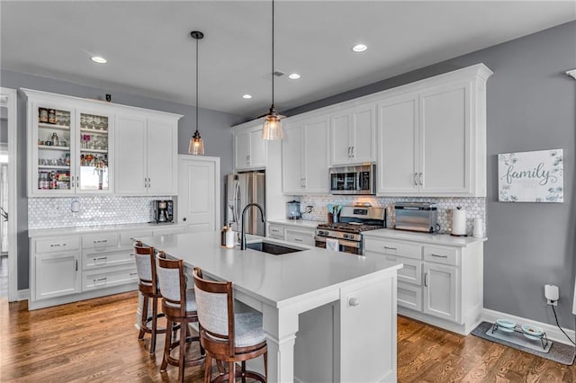 kitchen featuring stainless steel appliances, white cabinets, a sink, and wood finished floors