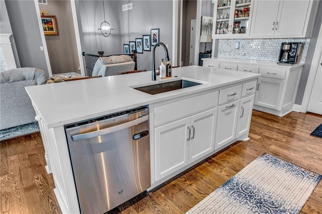 kitchen featuring a center island with sink, open floor plan, dark wood-type flooring, stainless steel dishwasher, and a sink