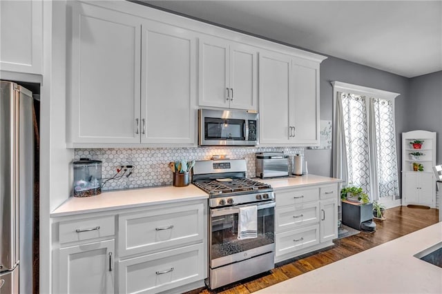 kitchen with a toaster, stainless steel appliances, white cabinetry, light countertops, and tasteful backsplash