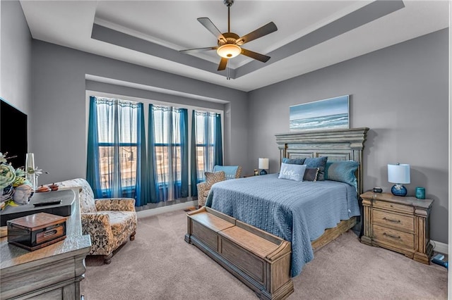 bedroom featuring ceiling fan, a tray ceiling, carpet flooring, and baseboards