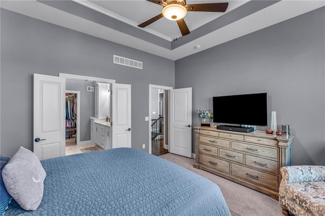 bedroom featuring visible vents, a raised ceiling, light colored carpet, a high ceiling, and a spacious closet