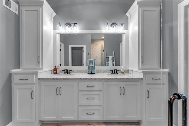 bathroom with double vanity, a shower with door, visible vents, and a sink