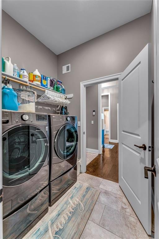 washroom featuring laundry area, visible vents, washer and clothes dryer, and baseboards