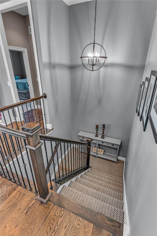 staircase featuring baseboards, a chandelier, and wood finished floors