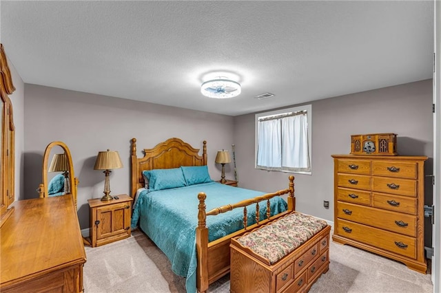 bedroom with light carpet, visible vents, and a textured ceiling