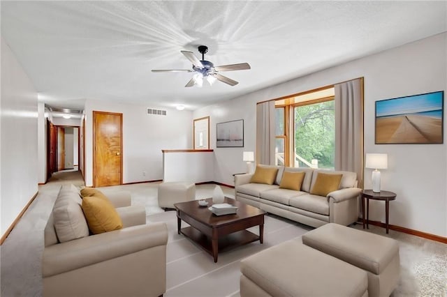 living room featuring baseboards, visible vents, a ceiling fan, and light colored carpet