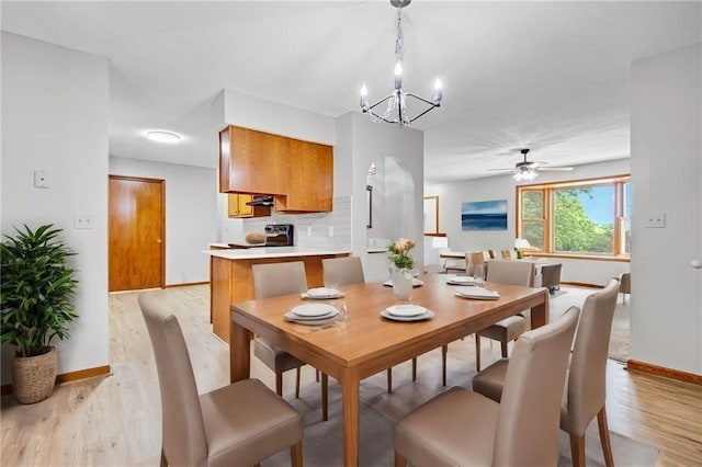 dining space featuring light wood-style floors, baseboards, and ceiling fan with notable chandelier