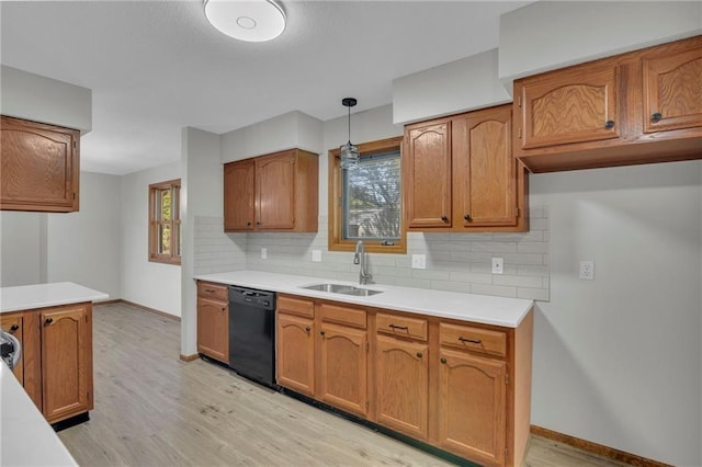 kitchen with brown cabinets, light countertops, decorative backsplash, a sink, and dishwasher