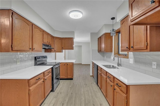 kitchen with light wood-style floors, under cabinet range hood, light countertops, black appliances, and a sink