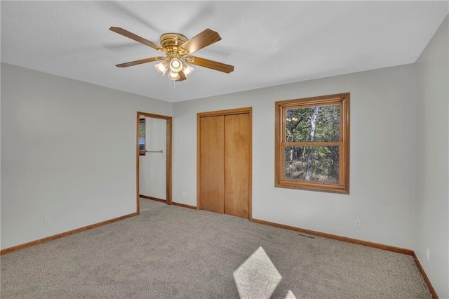 unfurnished bedroom with ceiling fan, a closet, baseboards, and carpet flooring