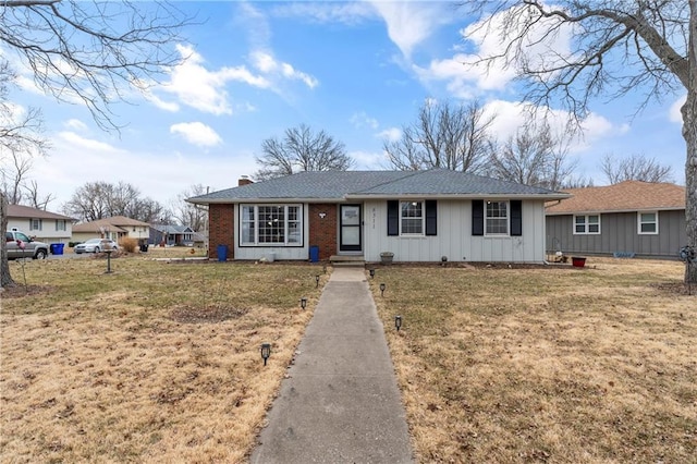 single story home with brick siding, a chimney, board and batten siding, and a front yard