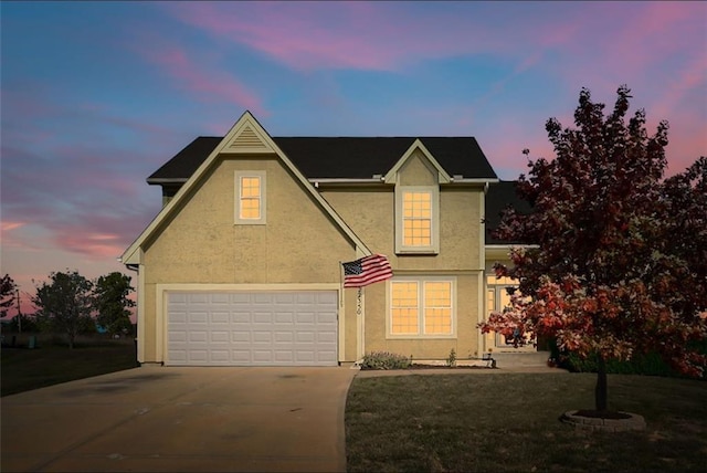 traditional home with a garage, concrete driveway, a front lawn, and stucco siding