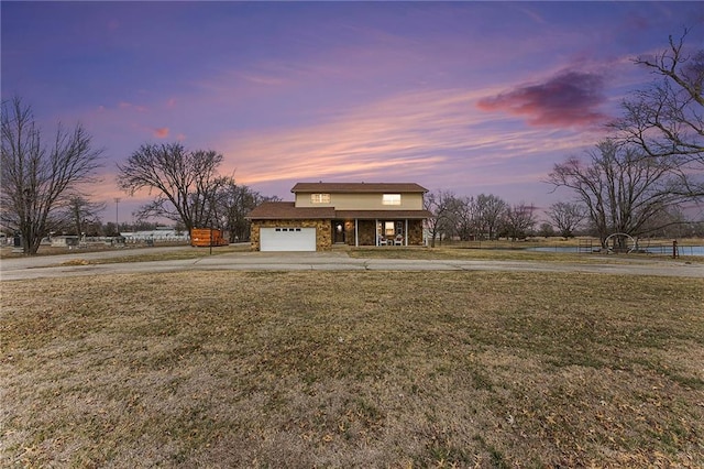 view of front of property featuring driveway, stone siding, a porch, and a front yard