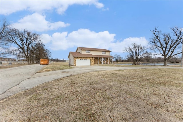 view of front facade with driveway, stone siding, a garage, and a front yard