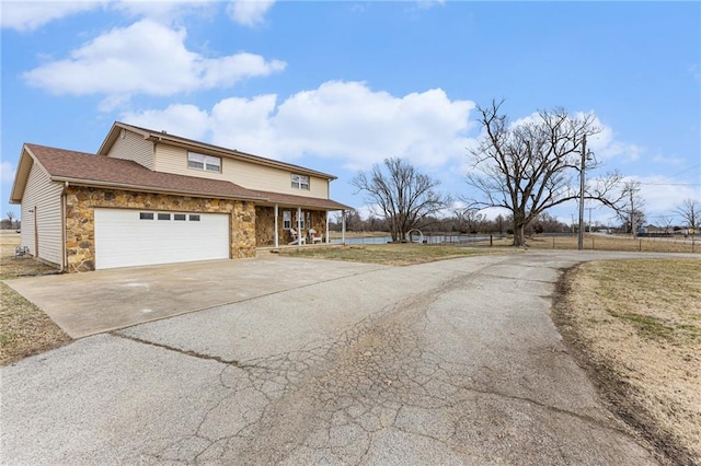 view of front of property featuring stone siding, concrete driveway, roof with shingles, and an attached garage