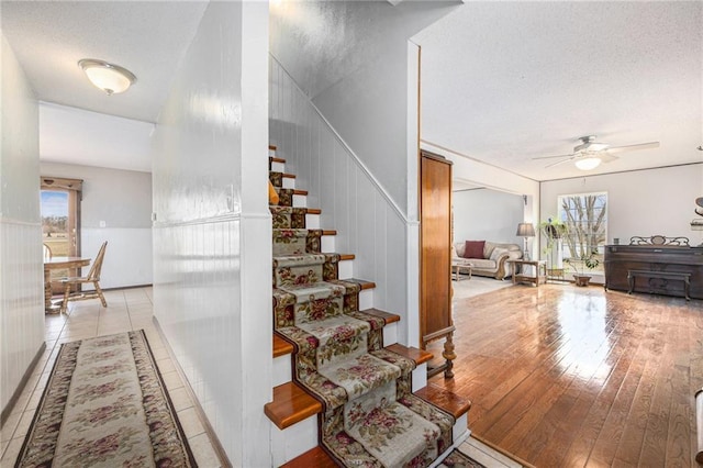 stairway with a wealth of natural light, wood-type flooring, and a textured ceiling