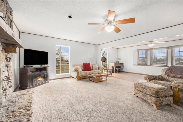 living area featuring a glass covered fireplace, a healthy amount of sunlight, and a textured ceiling