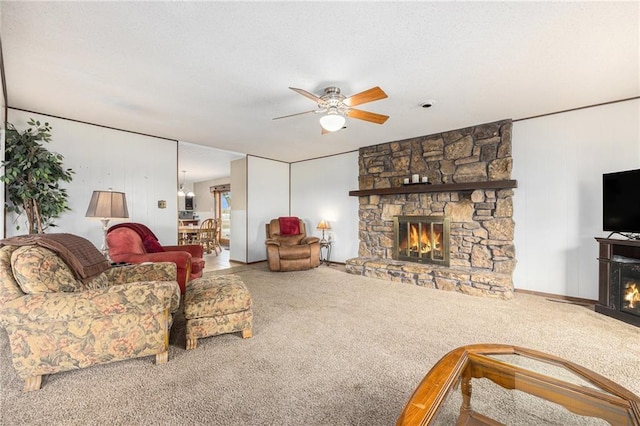 living room featuring carpet floors, ceiling fan, a fireplace, and a textured ceiling