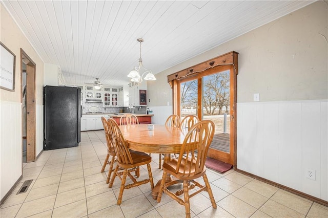 dining room featuring wood ceiling, wainscoting, visible vents, and light tile patterned floors