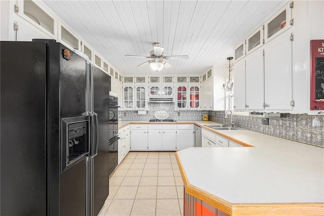 kitchen with light tile patterned flooring, a sink, light countertops, black appliances, and tasteful backsplash