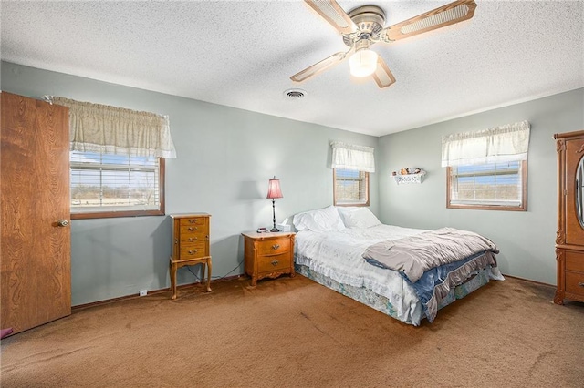 bedroom featuring a textured ceiling, carpet, visible vents, and a ceiling fan