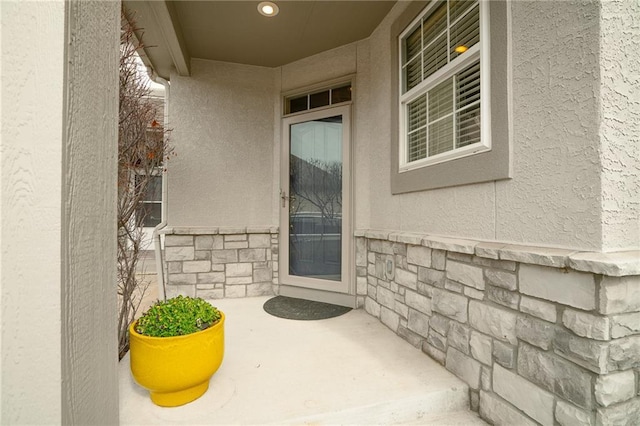 entrance to property featuring stone siding and stucco siding