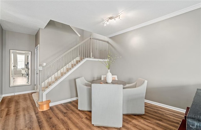 dining room with wood finished floors, baseboards, and stairs