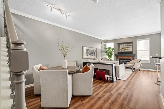 dining room with a textured ceiling, baseboards, wood finished floors, and a glass covered fireplace