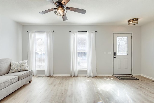 foyer entrance with light wood-type flooring, ceiling fan, visible vents, and baseboards