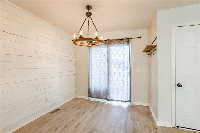 interior space with wooden walls, visible vents, baseboards, light wood-style flooring, and a chandelier