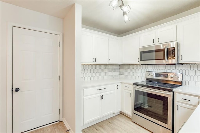 kitchen featuring tasteful backsplash, appliances with stainless steel finishes, light countertops, light wood-style floors, and white cabinetry