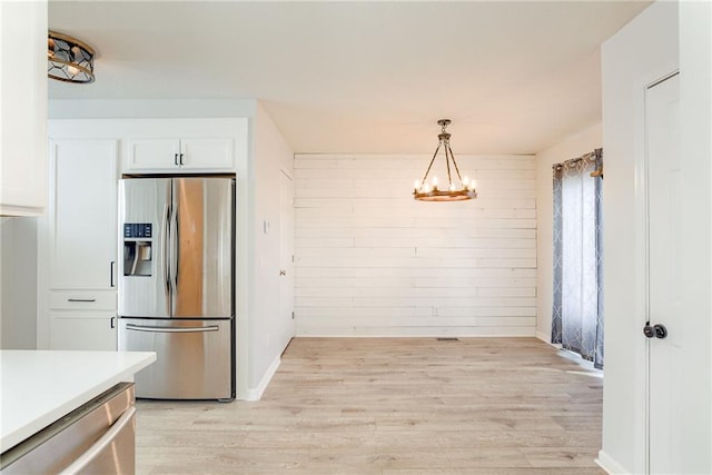 kitchen with a notable chandelier, appliances with stainless steel finishes, white cabinetry, and light wood-style floors