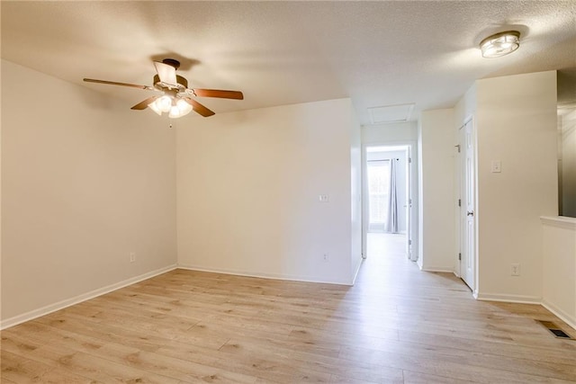 unfurnished room featuring attic access, baseboards, visible vents, a textured ceiling, and light wood-type flooring