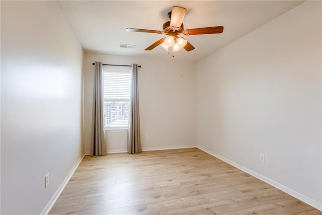 empty room featuring light wood-style floors, visible vents, and baseboards