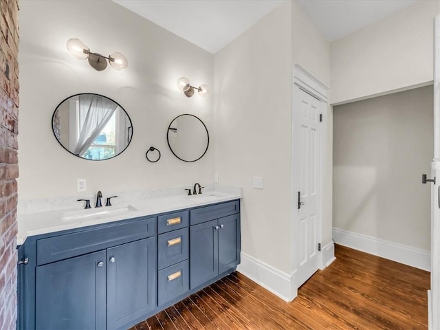 bathroom featuring double vanity, baseboards, a sink, and wood finished floors