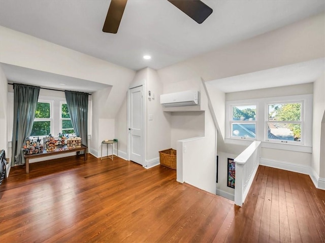 bonus room featuring a wealth of natural light, an AC wall unit, hardwood / wood-style floors, and a ceiling fan