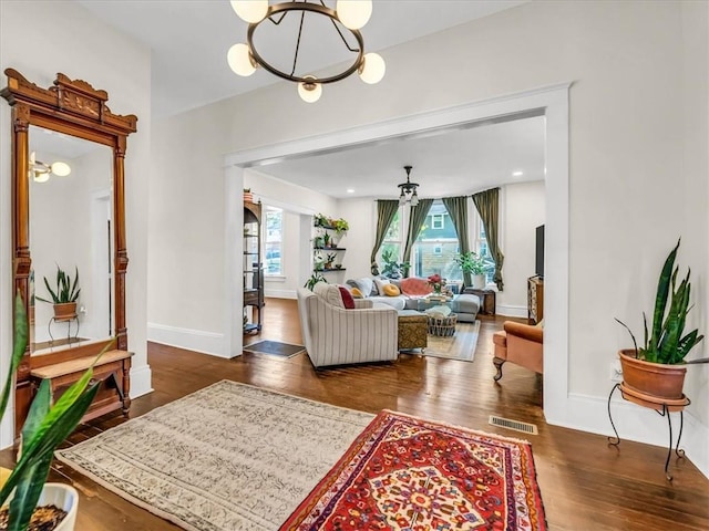 living room featuring wood finished floors, visible vents, baseboards, and an inviting chandelier