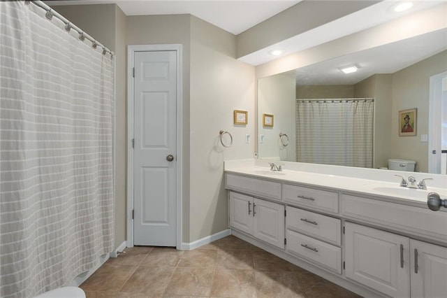 full bath featuring tile patterned floors, toilet, a sink, baseboards, and double vanity