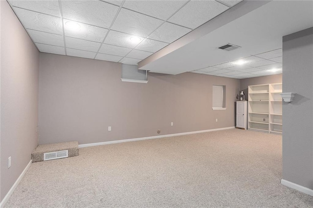 finished basement with baseboards, visible vents, and carpet floors